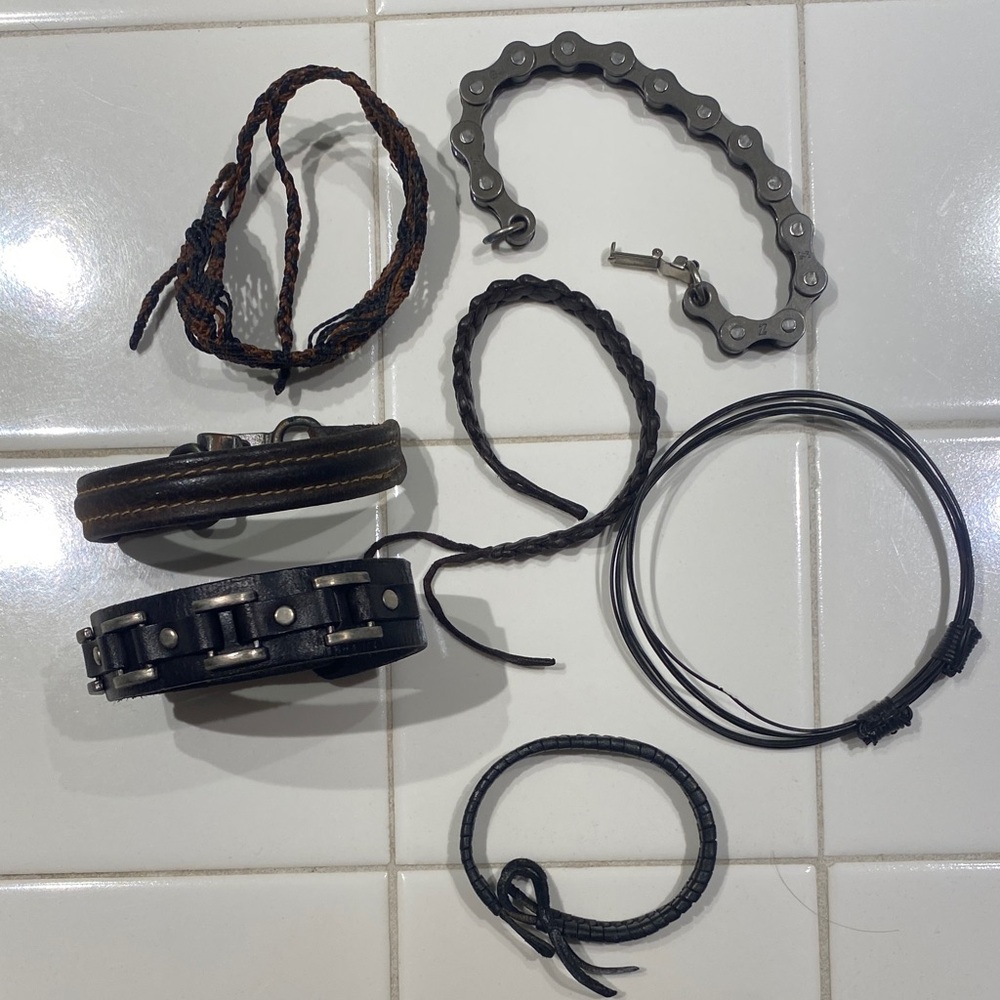 7 Assorted Black and Brown Bracelets with one bike chain style bracelet.